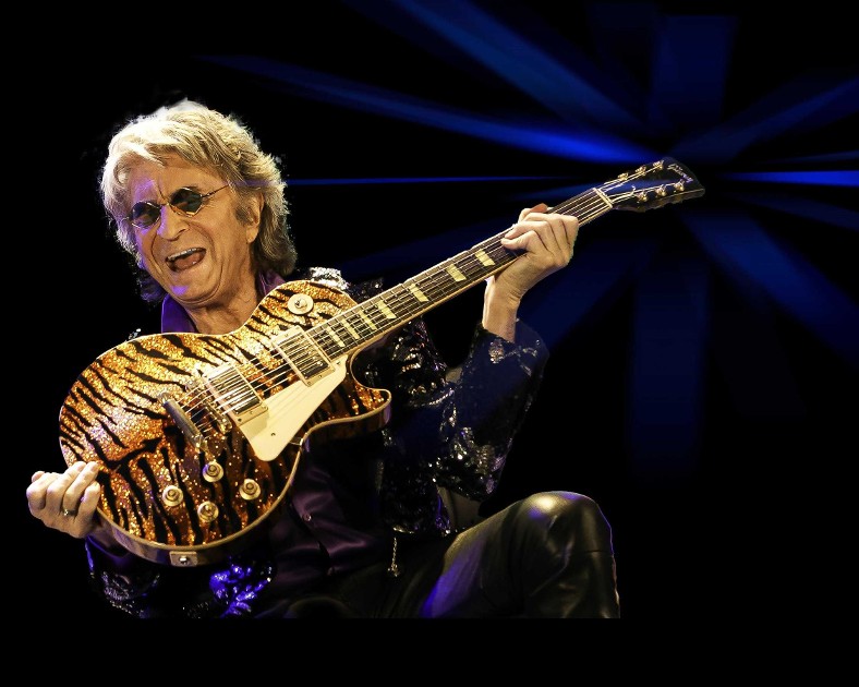 Jim Peterik plays a tiger-striped Gibson Les Paul guitar